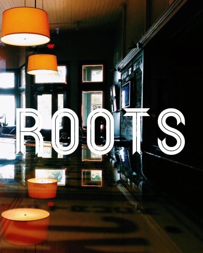 Inside Roots — the illuminated ROOTS sign reflected in the polished floor, with pendant lamps and candlelight